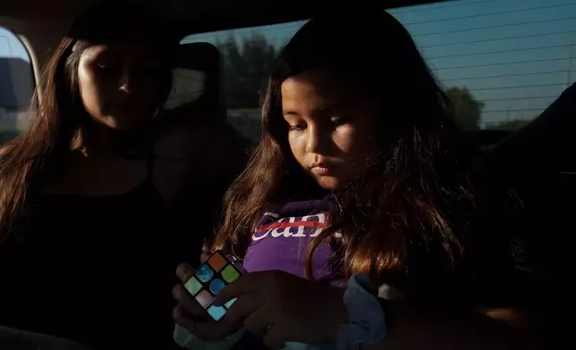 Kathryn Shergold, right, solves a Rubik's Cube in the car as her cousin Kimberly Ford, left, looks on, Sept. 14, 2026, in McAllen, Texas. (AP Photo/Julia Demaree Nikhinson)