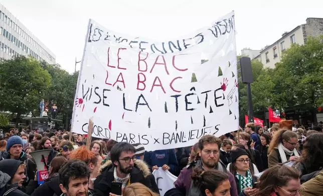 Protesters hold a banner reading : "High school students target the Bac. The Bac (Anti-Crime Brigade) target the head " as they gather against poor education school conditions in Paris, Thursday, Oct. 22, 2026. (AP Photo/Teresa Suarez)