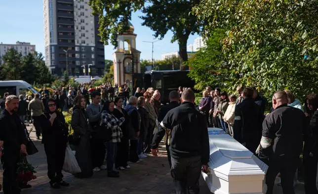 Funeral workers carry the coffin of 14-year-old Illia Honcharenko, who was killed in a Russian missile strike on a residential building on Sept. 30, during his funeral in Vyshhorod, Kyiv region, Ukraine, Friday, Oct. 2, 2026. (AP Photo/Evgeniy Maloletka)