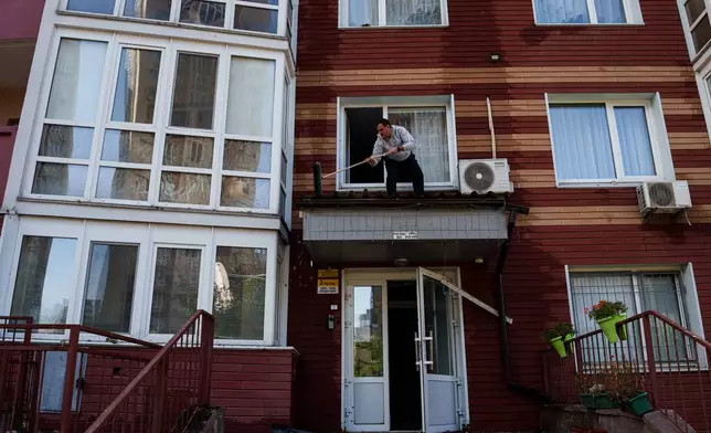 A man clears the rubble from a canopy over the entrance of a multi-storey residential building damaged following a Russian drone strike, in Kyiv, Ukraine, Friday, Oct. 2, 2026. (AP Photo/Evgeniy Maloletka)
