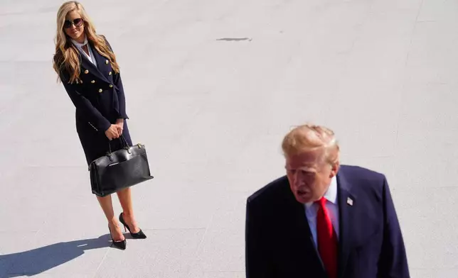 President Donald Trump speaks to the reporters as he walks to board Marine One on the South Lawn of the White House, Tuesday, Oct. 13, 2026, in Washington, as White House press secretary Katie Zacharia looks on. (AP Photo/Julia Demaree Nikhinson)