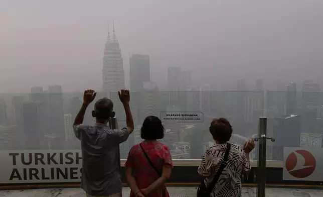 FILE - Visitors look out at the hazy skyline of Kuala Lumpur, Malaysia on Friday, Oct. 16, 2026. (AP Photo/Anton L. Delgado, File)