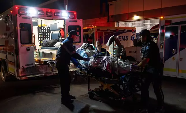 Paramedics load an injured person into an ambulance at the Wainwright Health center after a fire at Canadian Forces Base Wainwright, outside of Wainwright, Alberta Saturday, Oct. 17, 2026. (John Ulan/The Canadian Press via AP)