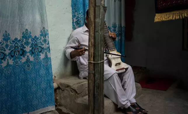 FILE - An Afghan musician poses for a portrait with his dilruba in Kabul, Afghanistan, Sept. 18, 2021. (AP Photo/Bernat Armangue, File)