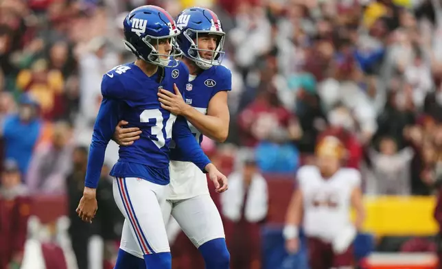 New York Giants' Jordan Stout (15) comforts Dominic Zvada (34) after Zvada missed a field goal during the overtime of an NFL football game against the Washington Commanders in Landover, Md., Sunday, Oct. 11, 2026. (AP Photo/Stephanie Scarbrough)