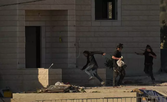 FILE - Israeli settlers are seen at one of the Palestinian houses belonging to the Tubasi family after they took it over in the West Bank village of Jalud, Aug. 25, 2026. (AP Photo/Leo Correa, File)