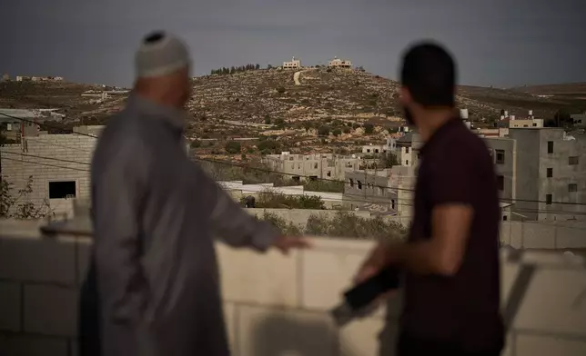 Mahmoud Tubasi, left, and his son Wael, over look their family's houses, which were burned by Israeli settlers in the West Bank village of Jalud, Tuesday, Oct. 20, 2026. (AP Photo/Leo Correa)