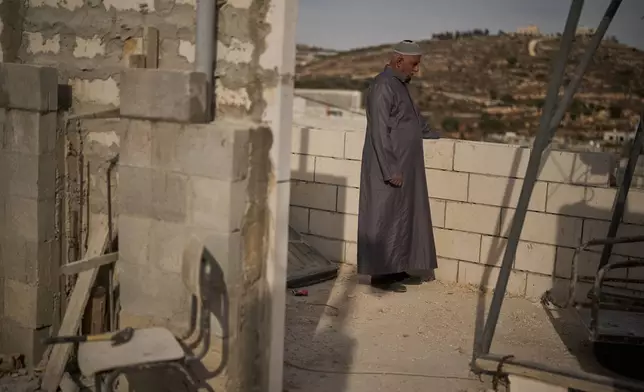 Mahmoud Tubasi stands on a rooftop near his two family's houses, which were burned by Israeli settlers in the West Bank village of Jalud, Tuesday, Oct. 20, 2026. (AP Photo/Leo Correa)
