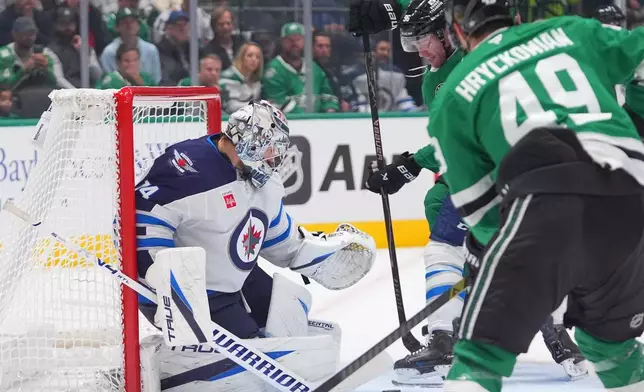 Winnipeg Jets goaltender Stuart Skinner (74) defends the goal against Dallas Stars right wing Mikko Rantanen (96) and center Justin Hryckowian (49) during the first period of an NHL hockey game Thursday, Oct. 22, 2026, in Dallas. (AP Photo/LM Otero)