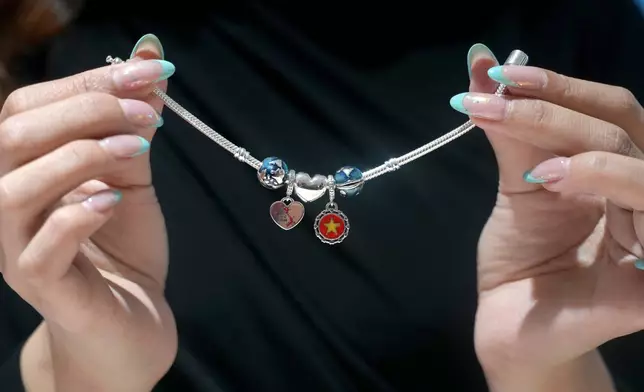 A model holds up a bracelet charm with trinkets of Vietnamese map and flags at the Pandora factory in Ho Chi Minh city, Vietnam, Wednesday, Sept.30, 2026. (AP Photo/Hau Dinh)