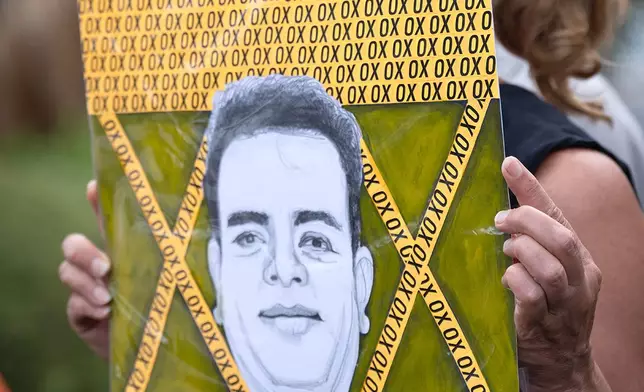 Sarah Fischer, a local artist who collaborates with Fiel to provide emergency portraiture, holds her artwork of Miguel Parra-Hernandez, during a press conference Monday, Oct. 12, 2026, near the scene on Clay Road near Texas 6 in Houston where Parra-Hernandez was struck by ICE agents after running from an SUV pursuing another man. (Jill Karnicki/Houston Chronicle via AP)