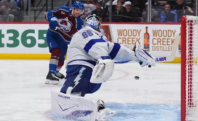 Colorado Avalanche defenseman Devon Toews, back, shoots the puck past Tampa Bay Lightning goaltender Andrei Vasilevskiy (88) for a goal in the first period of an NHL hockey game Friday, Oct. 23, 2026, in Denver. (AP Photo/David Zalubowski)