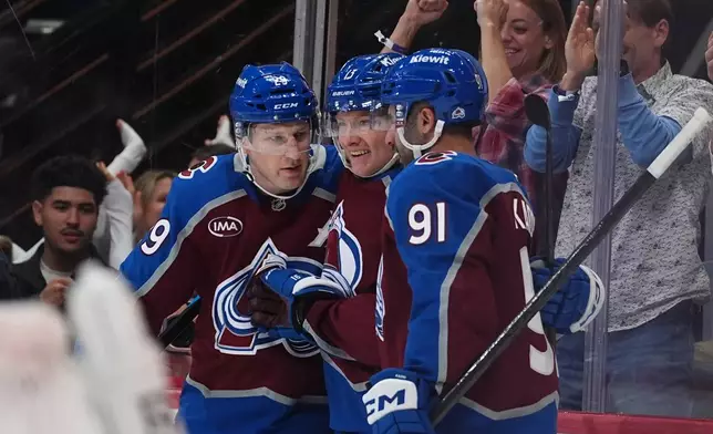 Colorado Avalanche center Nathan MacKinnon, left, and right wing T.J. Hughes, center, congratulate center Nazem Kadri (91) after his goal against the Tampa Bay Lightning in the first period of an NHL hockey game Friday, Oct. 23, 2026, in Denver. (AP Photo/David Zalubowski)