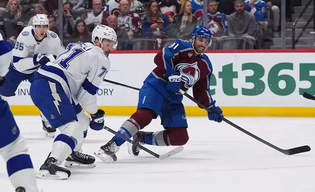 Colorado Avalanche center Nazem Kadri, right, falls as he shoots for a goal as Tampa Bay Lightning center Anthony Cirelli (71) and right wing Ilya Mikheyev (95) defend in the first period of an NHL hockey game Friday, Oct. 23, 2026, in Denver. (AP Photo/David Zalubowski)