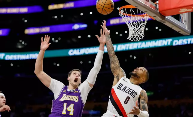 Portland Trail Blazers guard Damian Lillard (0), left, drives to the basket with the ball while being guarded by Los Angeles Lakers center Walker Kessler (14), right, during the first half of an NBA basketball game Tuesday, Oct. 27, 2026, in Los Angeles. (AP Photo/Caroline Brehman)