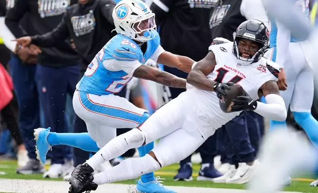 Houston Texans wide receiver Kayshon Boutte (14) catches a pass along the sideline as Tennessee Titans' Marcus Harris, left, defends during the second half of an NFL football game in Nashville, Tenn., Sunday, Oct. 11, 2026. (AP Photo/George Walker IV)