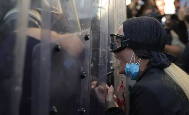 A protester reacts as riot police take cover behind their shields during an anti-government demonstration in Tirana, Albania, Friday, Oct. 16, 2026. (AP Photo/Hameraldi Agolli)