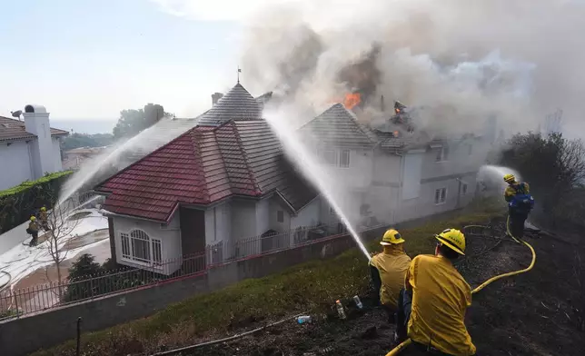 Firefighters work to douse a fire on house in flames during the Norte Fire on Friday, Oct. 16, 2026, in San Juan Capistrano, Calif. (AP Photo/Jae C. Hong)