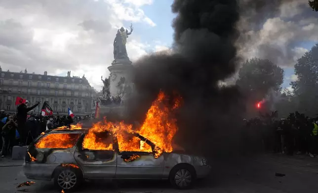 A car burns at Republique square during a protest against rising living costs, joining students' grievances, in Paris, Saturday, Oct. 17, 2026. (AP Photo/Thibault Camus)