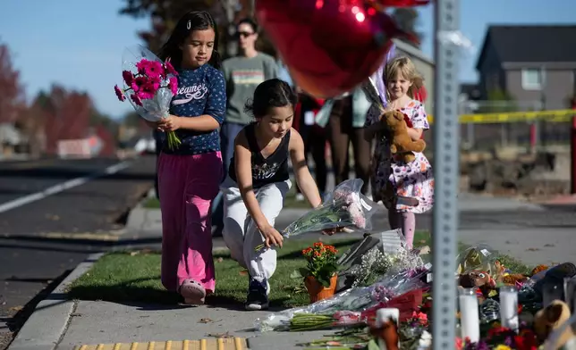 Children place flowers at a makeshift memorial outside Silver Rail Elementary in Bend, Ore., Friday, Oct. 16, 2026, a day after a deadly shooting. (AP Photo/Joe Kline)