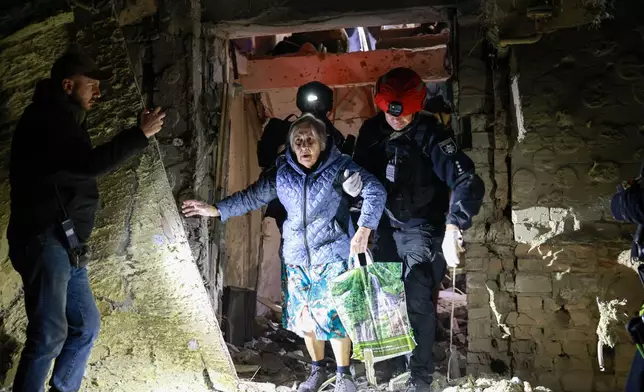 A policeman helps an elderly woman to walk out from a residential building damaged by a Russian airstrike in Zaporizhzhia, Ukraine, Saturday, Oct. 17, 2026. (AP Photo/Kateryna Klochko)