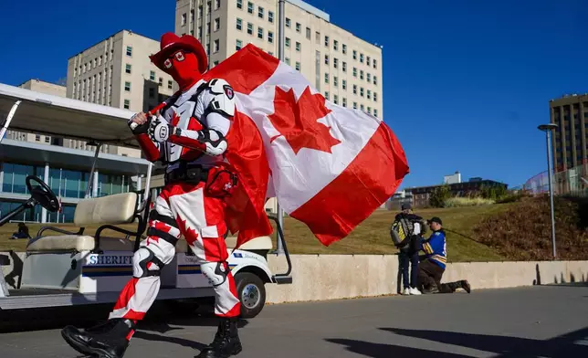 A supporter carries a Canadian flag at a pro-Canada rally in Edmonton, Alberta, Sunday, Oct, 18, 2026. (Timon Johnson/The Canadian Press via AP)