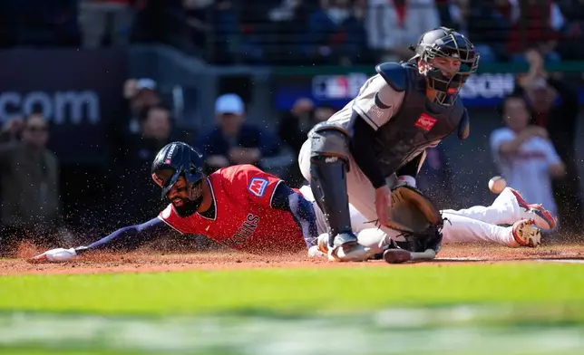 Cleveland Guardians' Jo Adell scores past Tampa Bay Rays catcher Liam Hicks on a double by Nathaniel Lowe during the second inning in Game 3 of an American League Championship Series baseball game in Cleveland, Thursday, Oct. 15, 2026. (AP Photo/David J. Phillip)