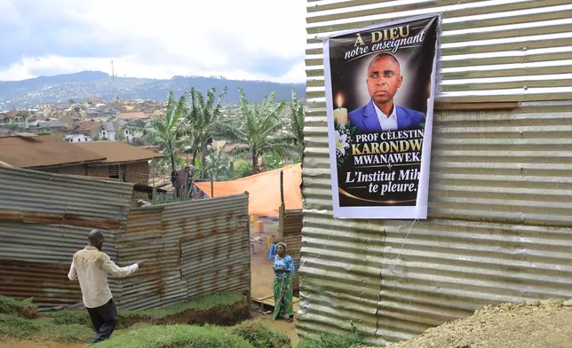 People walk past a banner with a photo of Marie-Célestin Karondwa, a local official who was beaten to death after publicly defending the government's response to Ebola, in Butembo, Congo, Wednesday, Sept. 30, 2026. (AP Photo/Sebastien Kitsa Musayi)