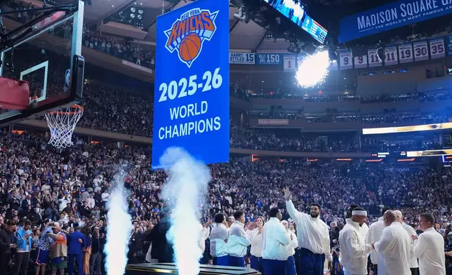New York Knicks center Karl-Anthony Towns waves as the Knicks 2025-26 World Champions banner is raised before an NBA basketball game between the New York Knicks and the Philadelphia 76ers Tuesday, Oct. 20, 2026, in New York. (AP Photo/Frank Franklin II)