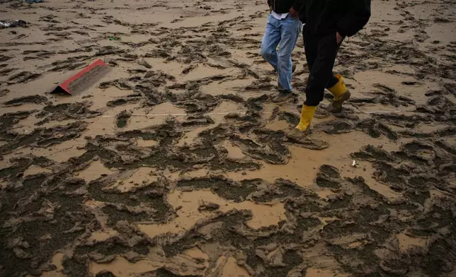 Local residents walk through the mud in the aftermath of floods caused by heavy rains, in Istanbul, Turkey, Thursday, Oct. 15, 2026. (AP Photo/Emrah Gurel)
