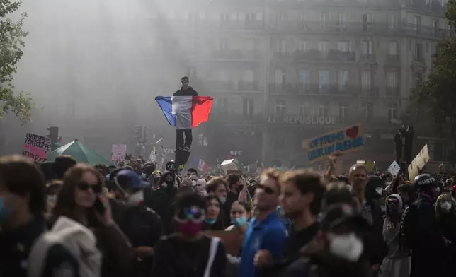 A protester holds a French flag at Republic Square during a demonstration against rising living costs, joining students' grievances, in Paris, Saturday, Oct. 17, 2026. (AP Photo/Thibault Camus)
