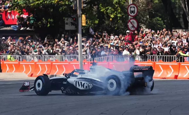 Mexican driver Sergio Perez of the Cadillac F1 Team burns rubber along Paseo de la Reforma during an exhibition in Mexico City, Wednesday, Oct. 28, 2026. (AP Photo/Eduarto Verdugo)