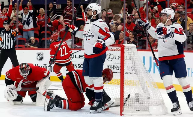 Washington Capitals' Alex Tuch (89) and Pierre-Luc Dubois, right, watch a replay of a goal as Carolina Hurricanes goaltender Brandon Bussi (32) and Sean Walker, center bottom, react during the first period of an NHL hockey game in Raleigh, N.C., Friday, Oct. 2, 2026. (AP Photo/Karl DeBlaker)