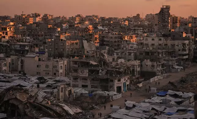 Palestinians walk along a street surrounded by buildings destroyed in Israeli military strikes during the Israel-Hamas war in Gaza City, Tuesday, Oct. 6, 2026. (AP Photo/Jehad Alshrafi)