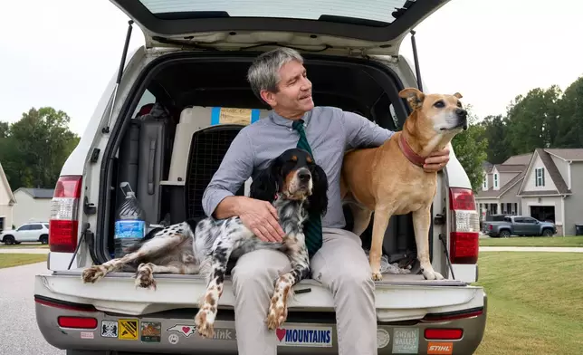 Paul Barringer, the Democratic nominee running for North Carolina's 13th Congressional District, poses for a photo with his dogs, Billie and Penny, on Oct. 8, 2026, in Garner, N.C. (AP Photo/Matt Ramey)