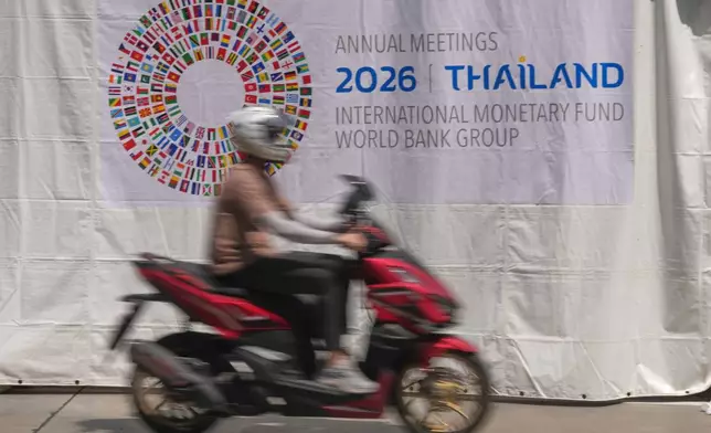 A motorcycle taxi rides past a banner at the Queen Sirikit National Convention Center ahead of the annual meetings of the International Monetary Fund (IMF) and the World Bank Group in Bangkok, Thailand, Friday, Oct. 9, 2026. (AP Photo/Sakchai Lalit)