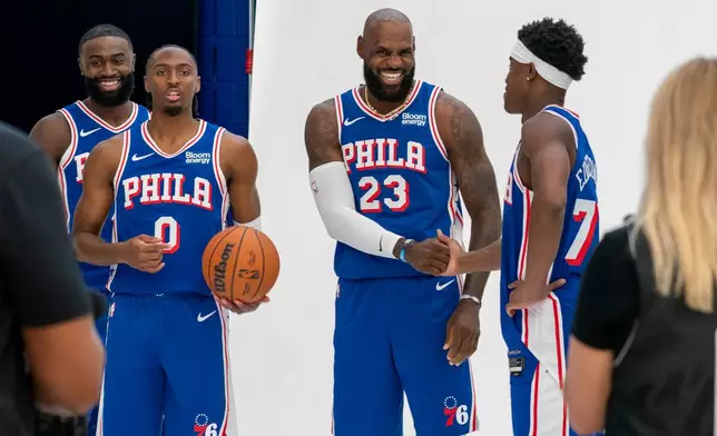 Philadelphia 76ers' LeBron James, center right, greats VJ Edgecombe, right, as they get ready for a group photos with Tyrese Maxey, center left, and Jaylen Brown, left, during the NBA basketball team's media day, Monday, Sept. 28, 2026, in Camden, N.J.. (AP Photo/Chris Szagola)