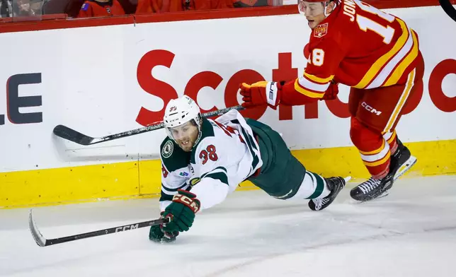 Minnesota Wild's Ryan Hartman, left, is checked by Calgary Flames' Ben Jones, right, during the third period of an NHL hockey game in Calgary, Alberta, Thursday, Oct. 22, 2026. (Jeff McIntosh/The Canadian Press via AP)
