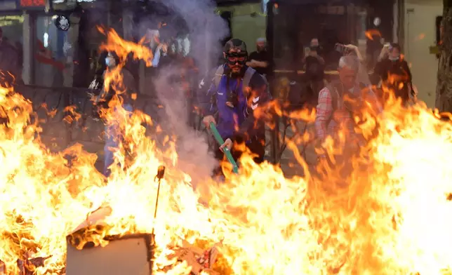 Protesters set fire to a barricade during clashes near the Education Ministry in Tirana, Albania, Tuesday, Oct. 13, 2026, joining a demonstration organized by the Flamingo protest movement demanding the resignation of Prime Minister Edi Rama. (AP Photo/Hameraldi Agolli)