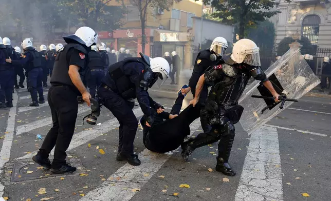 Riot police officers detain a hooded protester during clashes near the Ministry of Education in Tirana, Albania, Tuesday, Oct. 13, 2026, joining a demonstration organized by the Flamingo protest movement demanding the resignation of Prime Minister Edi Rama. (AP Photo/Hameraldi Agolli)