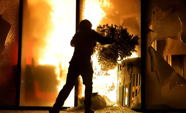 A hooded protester vandalizes the Justice Ministry during clashes in Tirana, Albania, Wednesday, Oct. 14, 2026, as students joined the Flamingo anti-government movement. (AP Photo/Hameraldi Agolli)