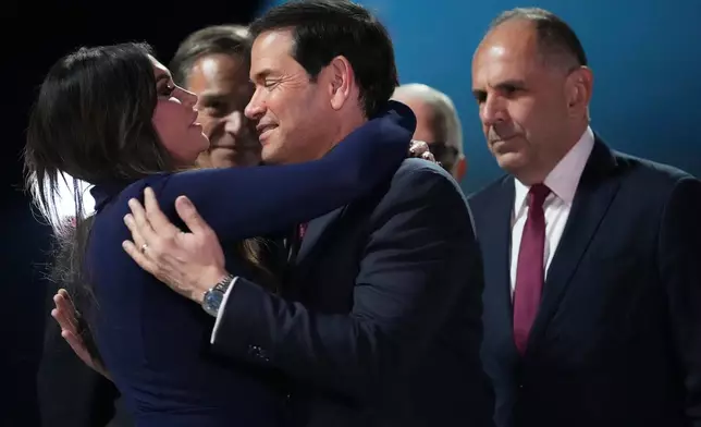 U.S. Secretary of State Marco Rubio, center, embraces U.S. Ambassador to Greece Kimberly Guilfoyle, left, as Greek Foreign Minister George Gerapetritis, right, looks on during Rubio's arrival at Eleftherios Venizelos International Airport near Athens, Greece, Tuesday, Oct. 6, 2026. (AP Photo/Mark Schiefelbein, Pool)