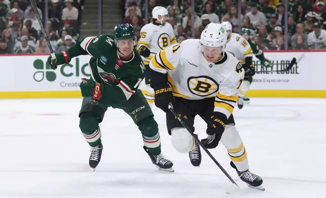 Minnesota Wild center Joel Eriksson Ek (14) and Boston Bruins center Casey Mittelstadt (11) skate after the puck during the first period of an NHL hockey game Saturday, Oct. 3, 2026, in St. Paul, Minn. (AP Photo/Bailey Hillesheim)