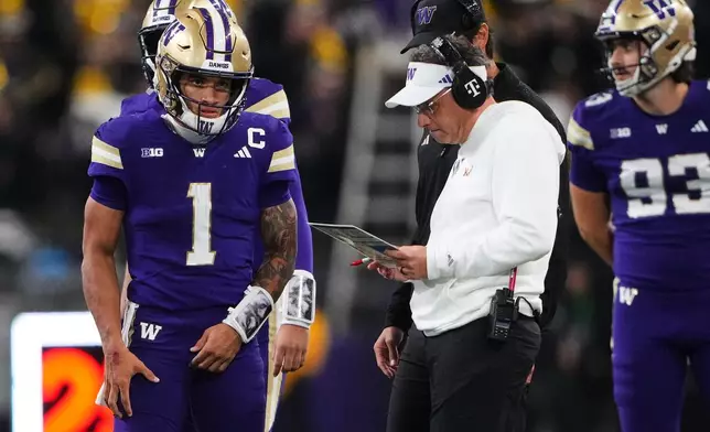 Washington quarterback Demond Williams Jr. (1) stands with head coach Jedd Fisch during a timeout against Iowa during the first half of an NCAA college football game, Friday, Oct. 9, 2026, in Seattle. (AP Photo/Lindsey Wasson)