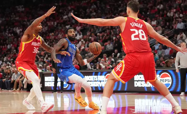 Dallas Mavericks guard Kyrie Irving, center, controls the ball against Houston Rockets' Marcus Smart (36) and Alperen Sengun (28)during the first half of an NBA basketball game, Wednesday, Oct. 21, 2026, in Houston. (AP Photo/Karen Warren)