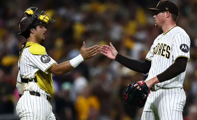 San Diego Padres pitcher Mason Miller, right, and catcher Ethan Salas, left, celebrate after their team won a baseball game against the Arizona Diamondbacks, Saturday, Sept. 26, 2026, in San Diego. (AP Photo/Karl Anderson)