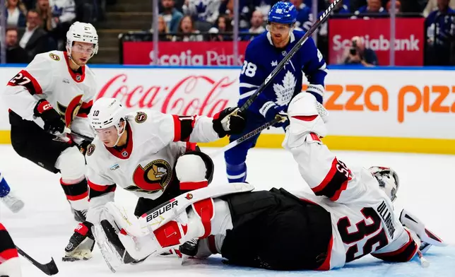 Ottawa Senators goaltender Linus Ullmark (35) makes a save as Senators' Jordan Spence (10) pushes away the rebound and Toronto Maple Leafs' William Nylander (88) looks on during the second period of an NHL hockey game in Toronto, Saturday, Oct. 3, 2026. (Frank Gunn/The Canadian Press via AP)