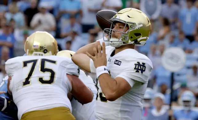 Notre Dame quarterback CJ Carr, right, looks to pass against North Carolina behind the block of offensive lineman Sullivan Absher (75) during the first half of an NCAA college football game Saturday, Oct. 3, 2026, in Chapel Hill, N.C. (AP Photo/Chris Seward)