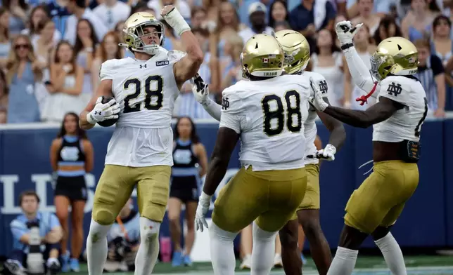 Notre Dame safety Luke Talich (28) celebrates his interception with defensive lineman Armel Mukam (88) and other teammates during the first half of an NCAA college football game against North Carolina, Saturday, Oct. 3, 2026, in Chapel Hill, N.C. (AP Photo/Chris Seward)