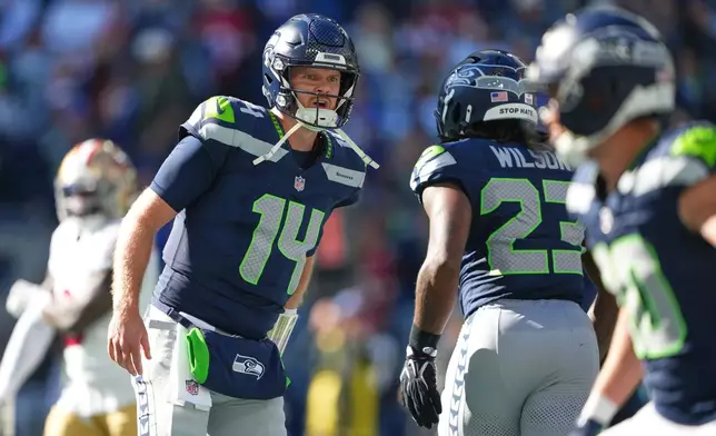 Seattle Seahawks quarterback Sam Darnold (14) reacts with running back Emanuel Wilson (23) after Wilson scored on a run against the San Francisco 49ers during the first half of an NFL football game Sunday, Oct. 11, 2026, in Seattle. (AP Photo/Lindsey Wasson)